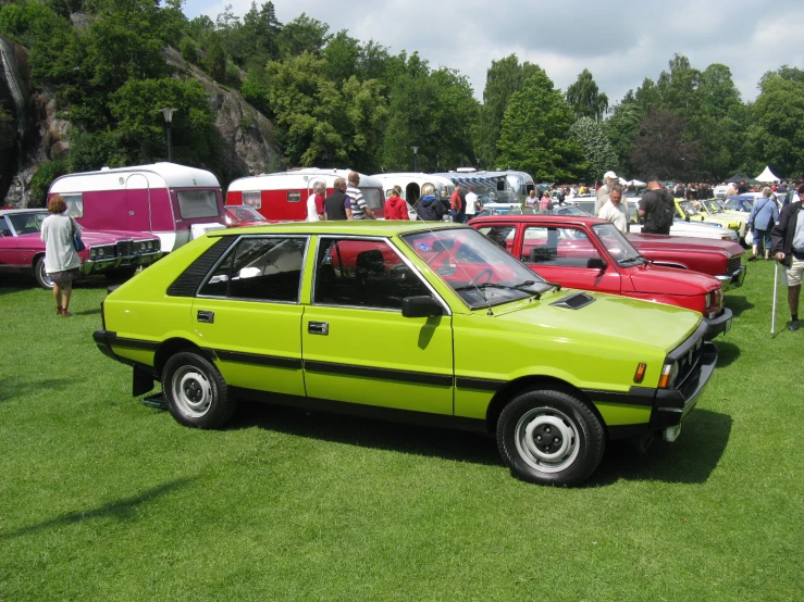 a group of cars in a grassy area next to a tent