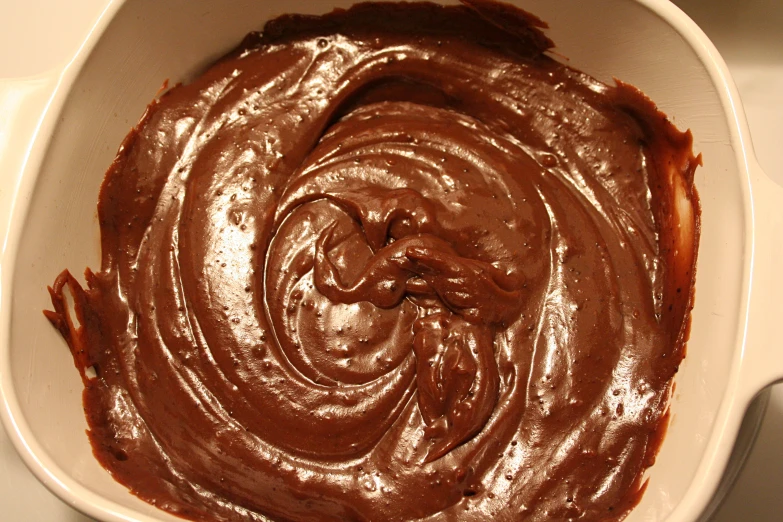 the chocolate sauce in a white bowl is swirled