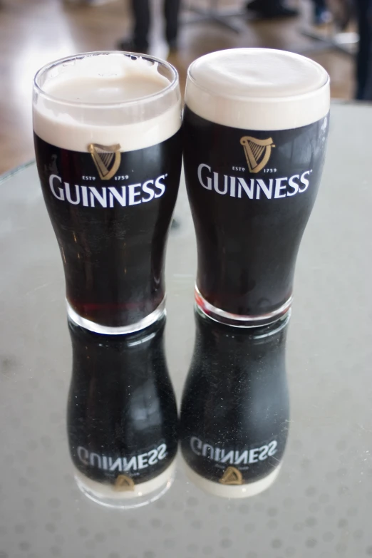 guinness beer mugs sit on top of the glass table