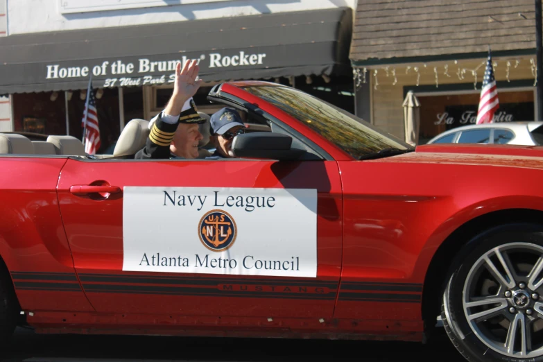 a man in a red convertible is waving to someone out the window