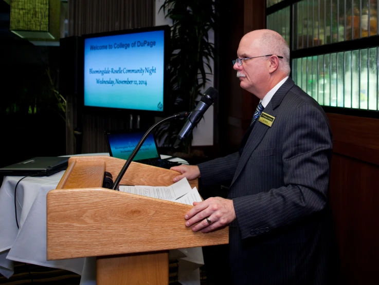 a man in a suit standing at a podium with an open book in front of him