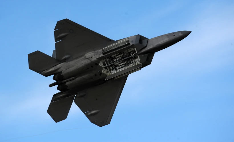 a fighter jet flies in the air with clear sky behind it