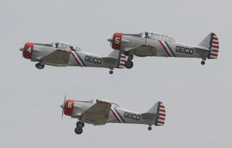 two red, white and blue airplanes fly through the gray sky