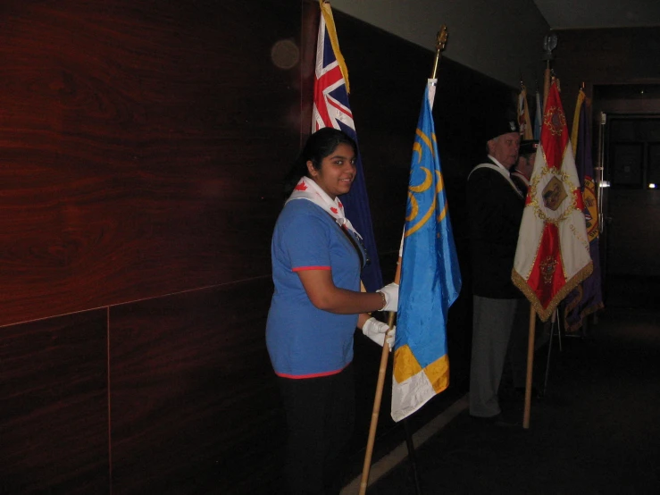 a woman holds several flags in one hand and an official man stands with his other