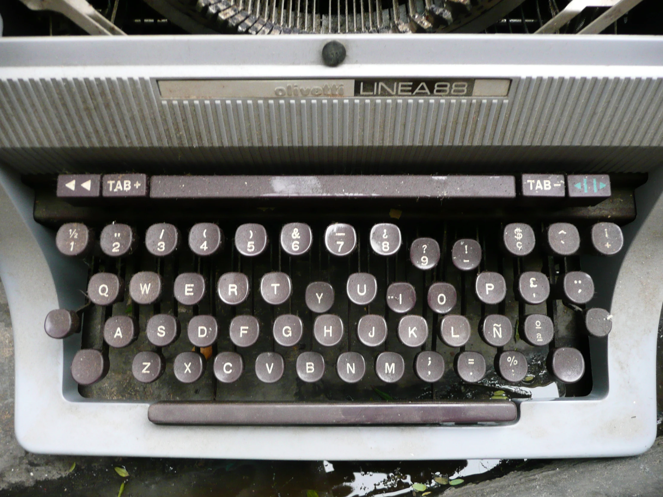 a typewriter sitting on top of concrete next to water