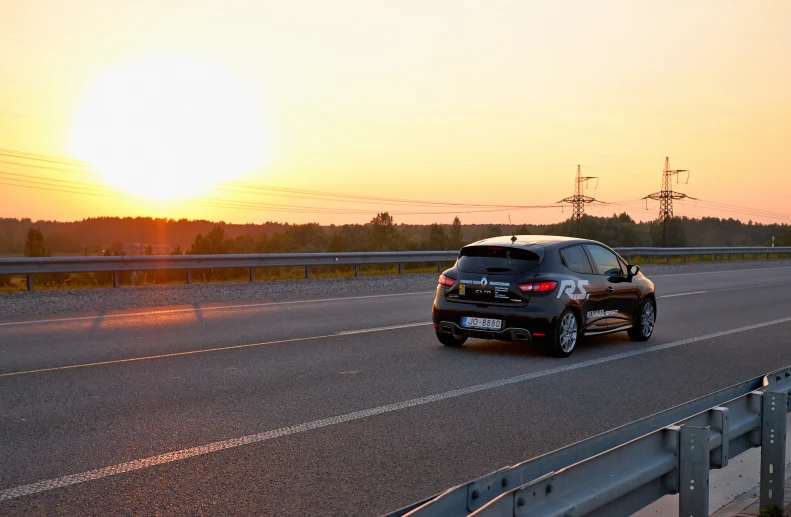 an suv driving on a highway with the sun rising behind it