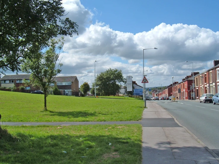 cars are driving on the road between houses and lawn