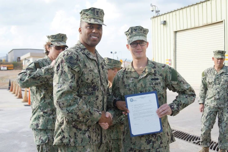 men in camouflage uniforms hold up a certificate