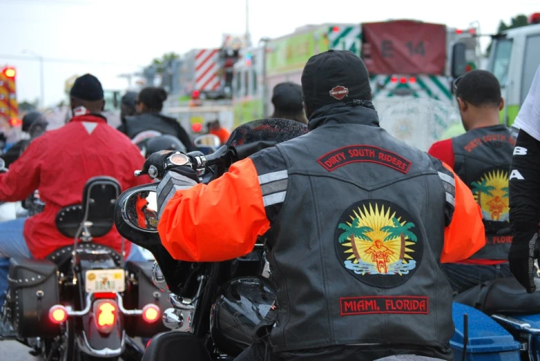 several bikers in the road driving down the street