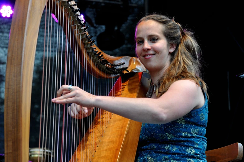 a woman in blue dress holding a harp