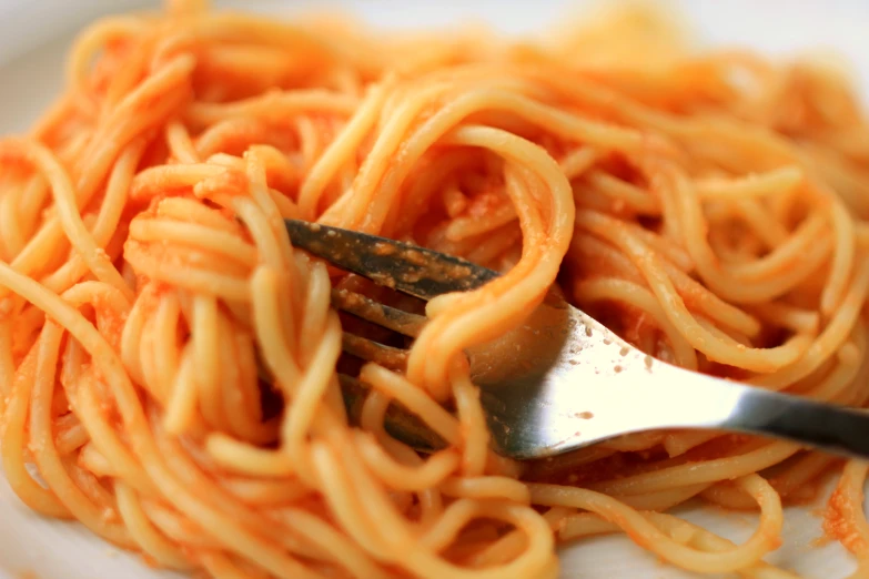 spaghetti is being eaten by a fork and spoon