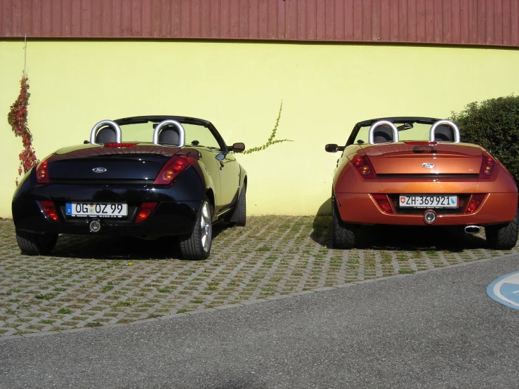 a yellow and a red convertible car parked next to each other