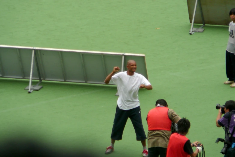 man in white shirt throwing tennis ball on green court with spectators