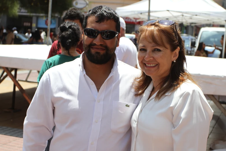 two people standing beside each other with tents in the background