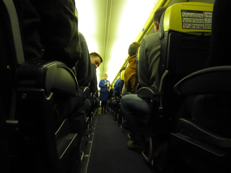 the aisle area of an airplane with people seated and facing the opposite way