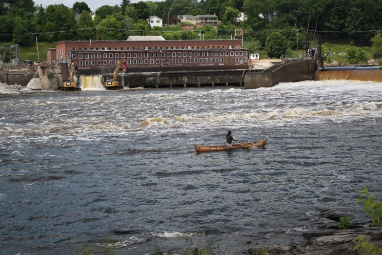 a canoe is rowing towards a brick structure across a river