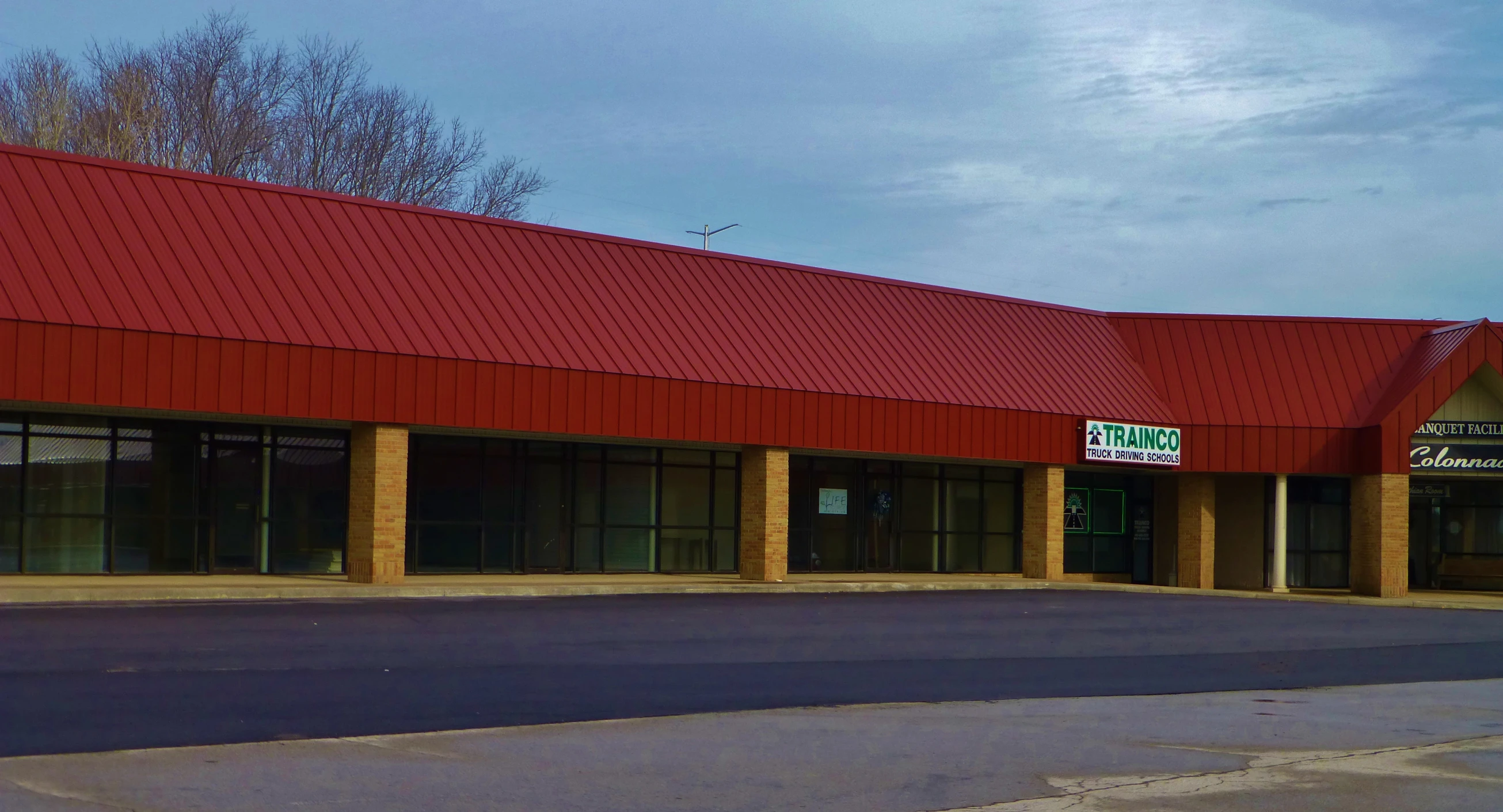 a commercial building with red roof and brick columns