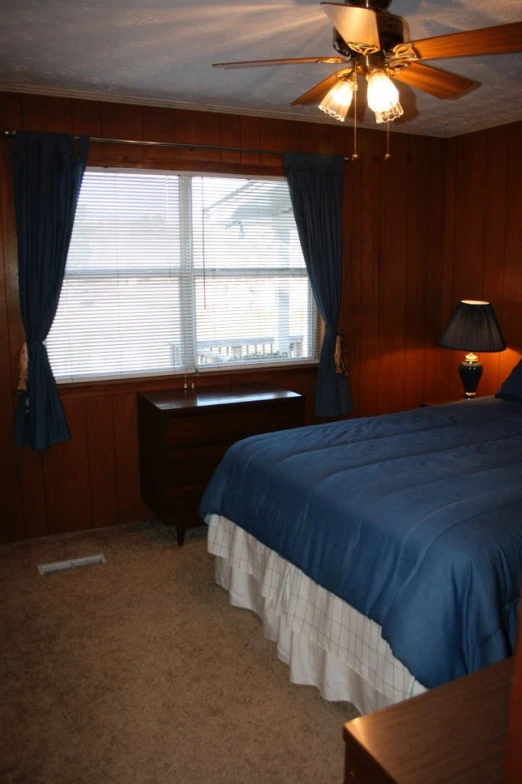 a bed room with a neatly made bed and a fan