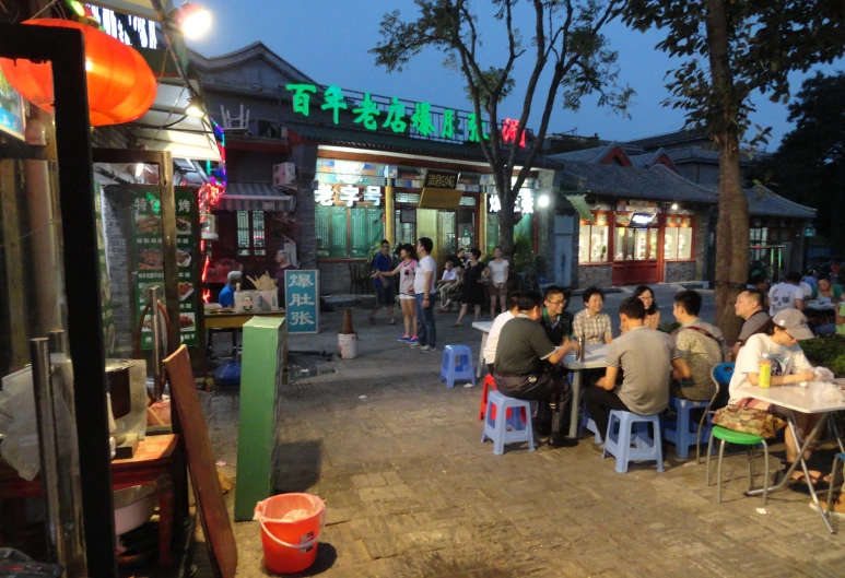 several people sitting at tables outside of a restaurant