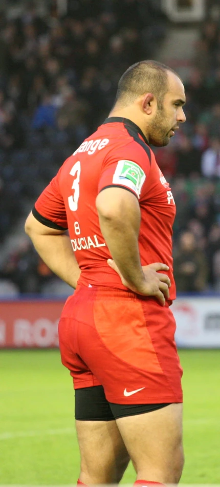 a rugby player in the middle of a game, with the referee standing behind him