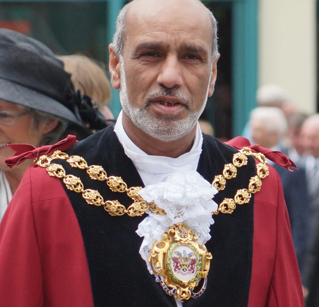 a man wearing a robe and a white beard with an elaborate necklace on his neck