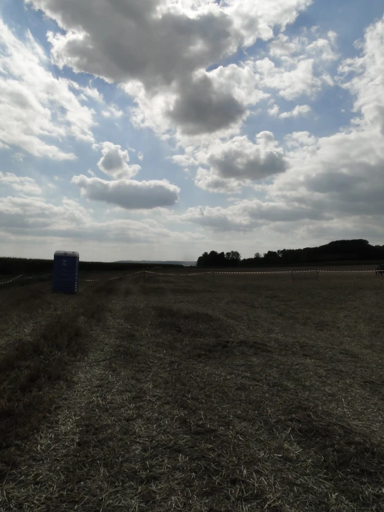 two empty bales and a small dirt field with trees on the horizon
