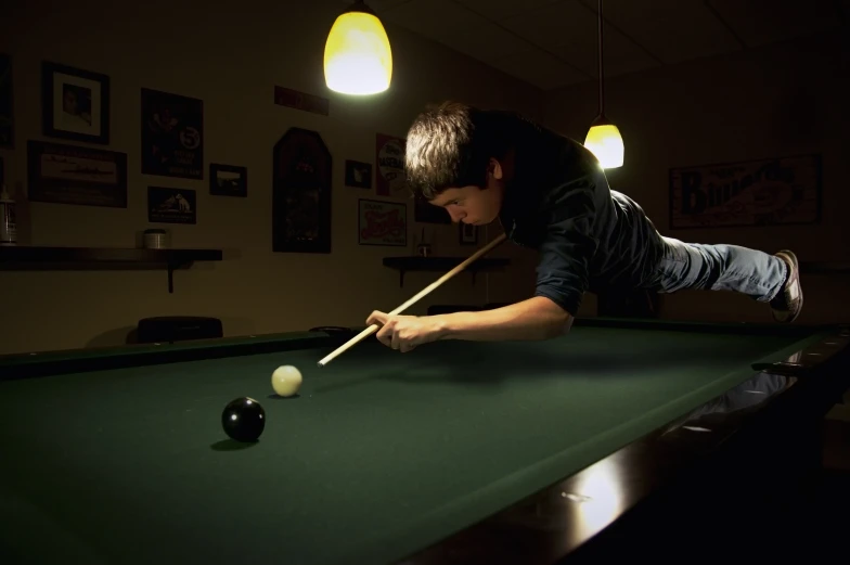 the boy is playing pool on the pool table