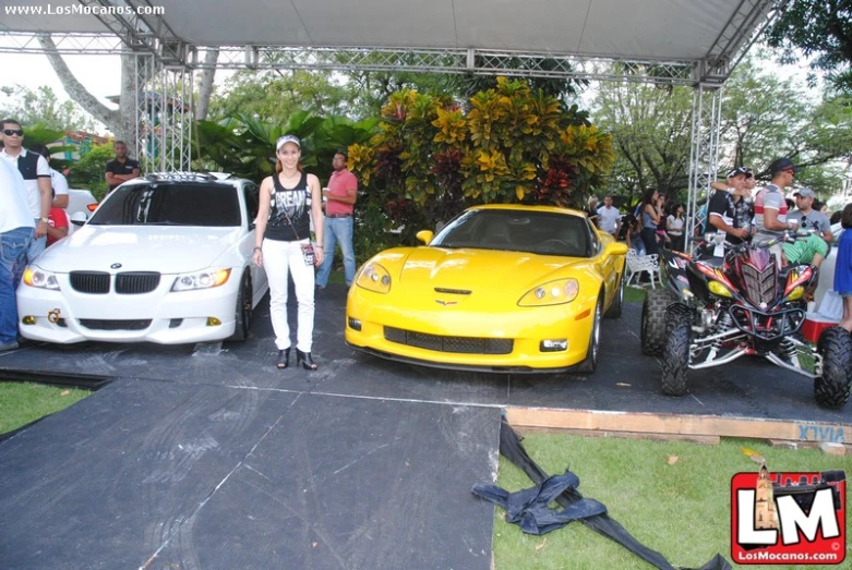 two cars with people standing around in front of it