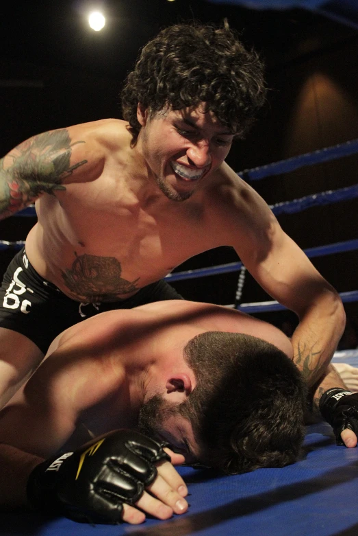 two men wrestling with one laying on the ground