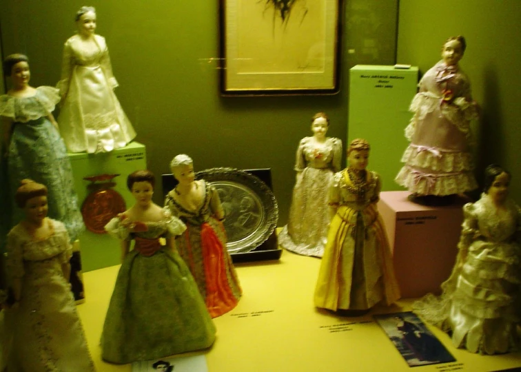 this room features green walls, many dressed up and dressed in period dresses