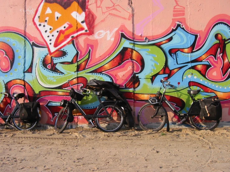 three motorcycles in front of colorful graffiti on a wall
