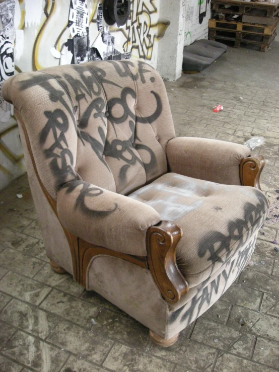 a chair with graffitti on it sitting in front of a graffiti covered wall