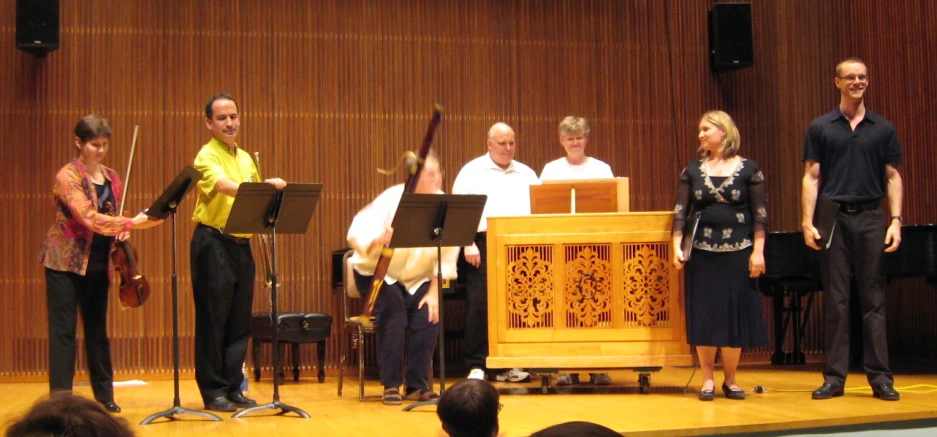 some musicians stand near an organ in front of a crowd