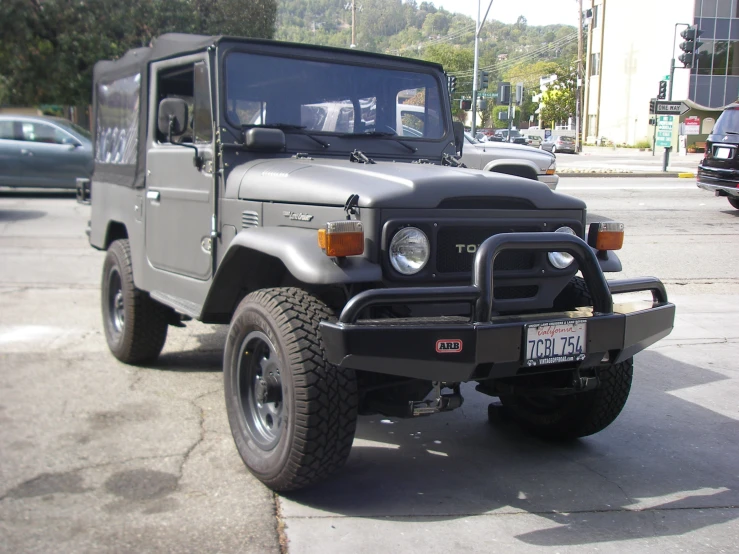 a gray and black jeep parked next to other cars