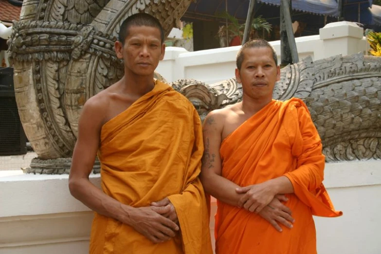 two young monks posing for po with large statue behind them