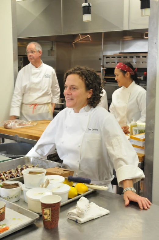 three chefs preparing food and cooking in a kitchen