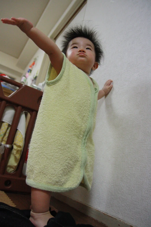 a baby boy standing in a closet with a towel around his shoulders