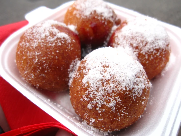 a foam container with a small pile of doughnuts in it