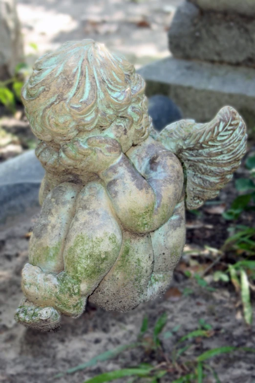 a stone statue of a little angel holding a heart