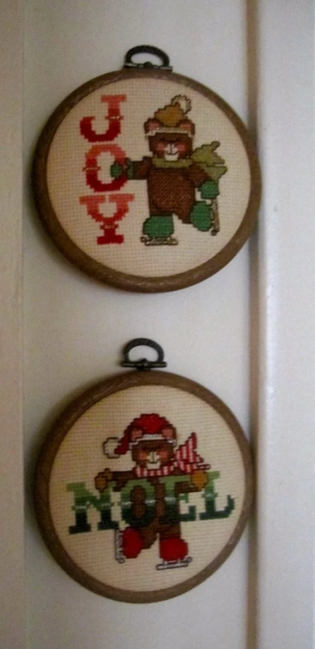 two cross stitch wall hangings next to a door