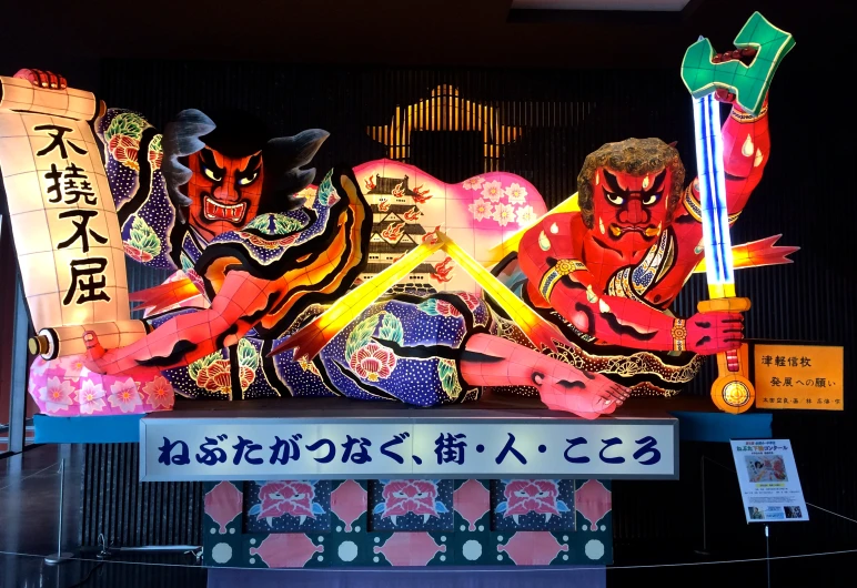 a neon display on the wall with a couple of men dressed as demon cats