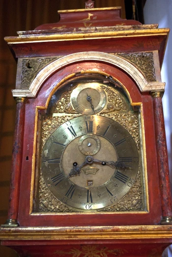 an old red clock that is hanging up on a wall