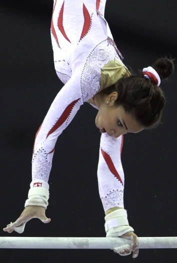 a female professional gymnastics competitor leaning down with her hand on the back of the balance beam