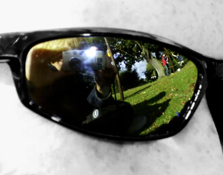 the reflection of a man wearing sunglasses with his reflection in the lens