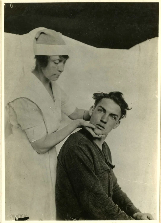 a nurse adjusting a doctor's cap while sitting in front of an image of a patient