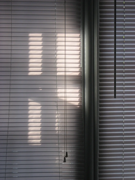 a person is silhouetted in a window behind blinds