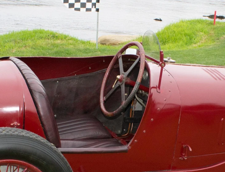 an old style red car driving on grass