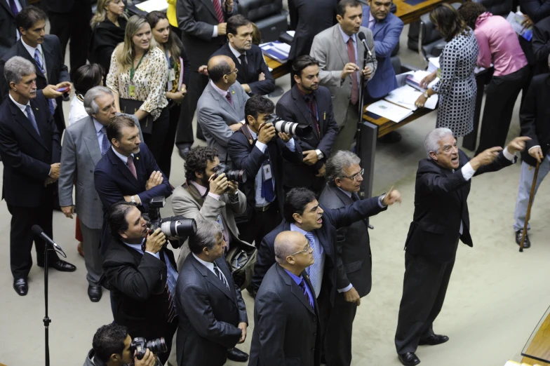 several people in a crowd holding cameras looking up