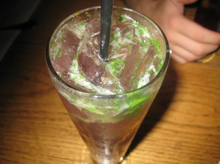 someone is sitting at a wooden table with an iced drink