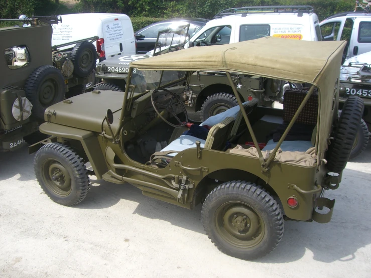 there is a green jeep that has some army vehicles parked